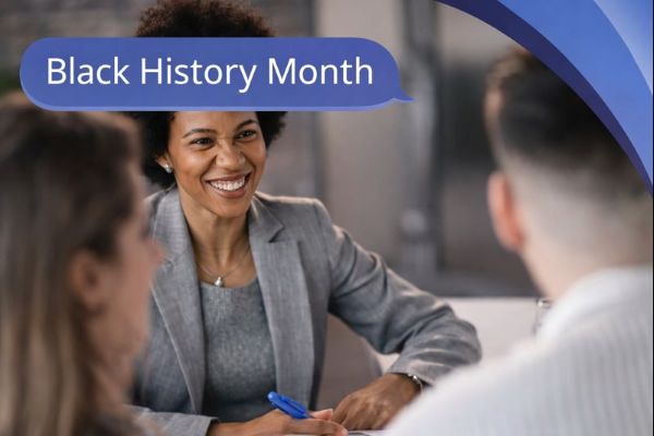 A smiling Black woman in a grey blazer speaks with two people in an office setting, with the others shown out of focus in the foreground. A blue speech bubble in Open Sans reads “Black History Month,” with curved blue Connect Mortgages brand accents in the top-right corner.