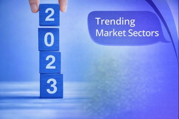 A blue-toned promotional graphic shows a hand stacking four blue wooden blocks that read “2023” on the left, with a large speech-bubble headline on the right saying “Trending Market Sectors,” over a soft gradient background with curved Connect-style swooshes along the right edge.
