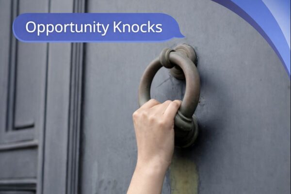 A close-up of a hand holding a large metal door knocker on a dark grey door. In the top-left, a blue speech bubble in Open Sans reads “Opportunity Knocks,” and curved blue Connect Mortgages brand accents appear in the top-right corner.