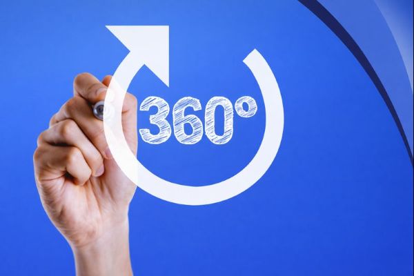 A close-up of a hand holding a pen in front of a blue Connect Mortgages branded background. A large white circular arrow surrounds the text “360° 360 Portfolio Review” in Open Sans, with curved blue brand accents in the top-right corner.