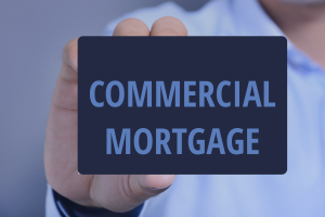 Close-up of a person holding a business card that reads “Commercial Mortgage,” styled in brand light blue and dark blue tones, representing commercial property finance.